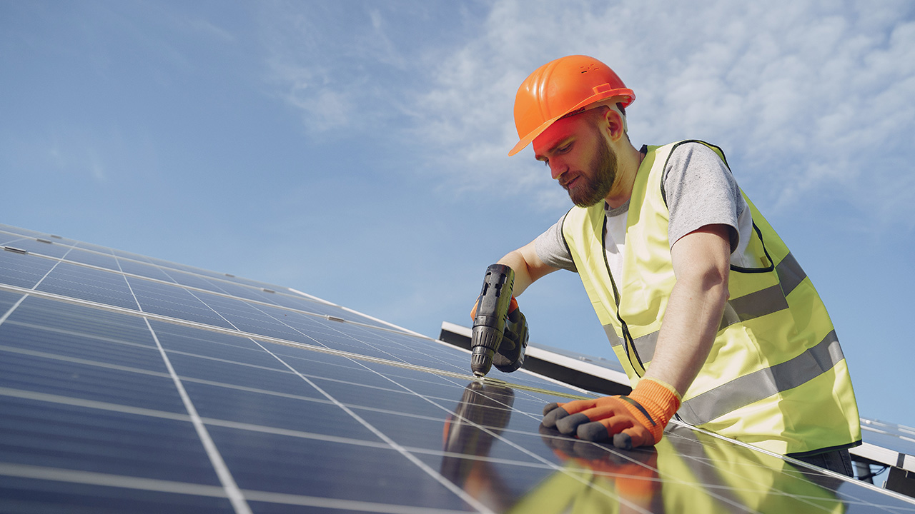 Man in a protective helmet installing solar panel system