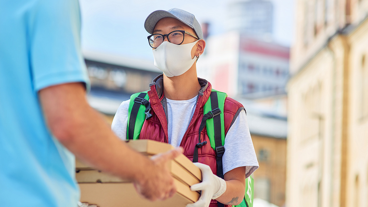 Asian delivery man giving pizza to customer