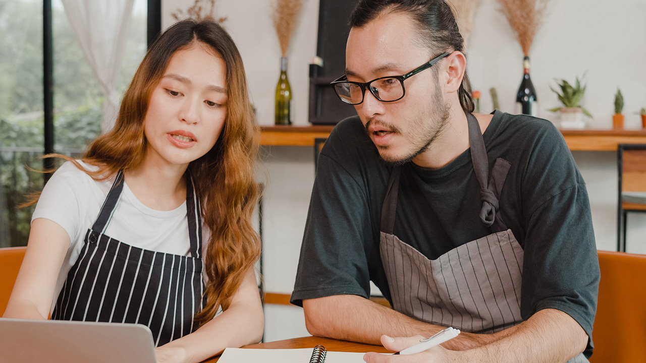 Small business owners couple using laptop discussing project