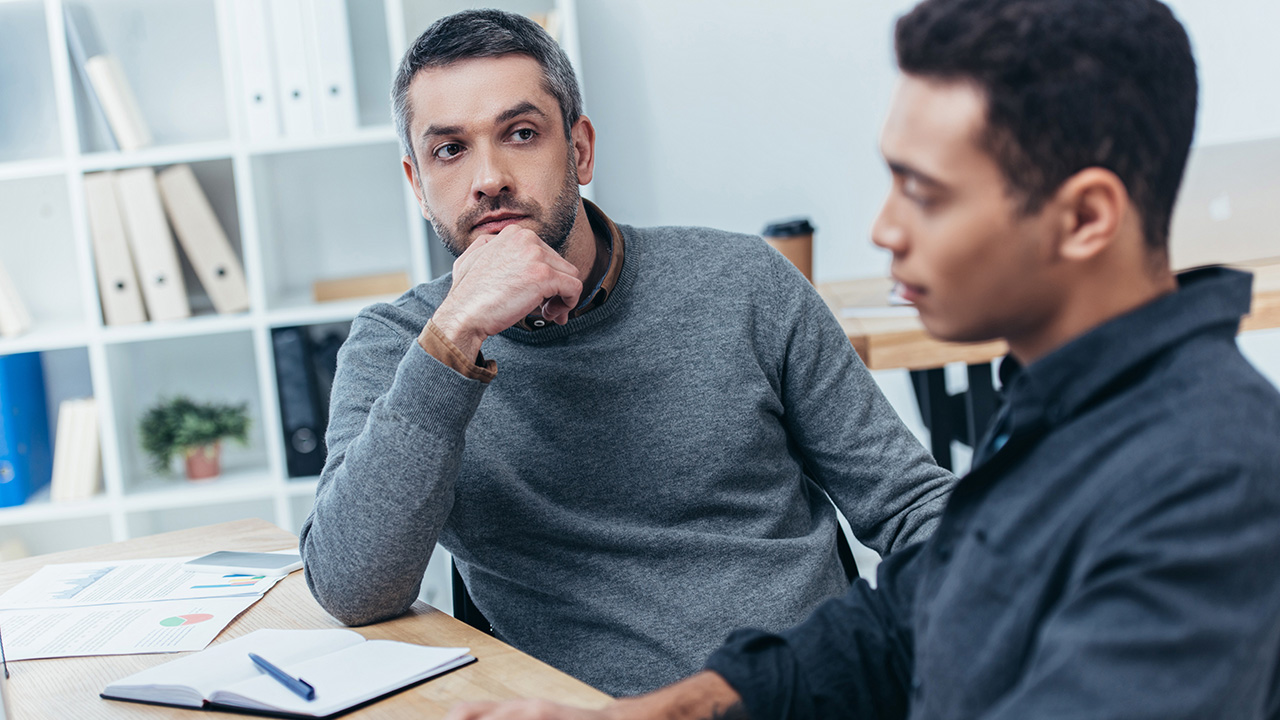 Business mentor looking at young colleague