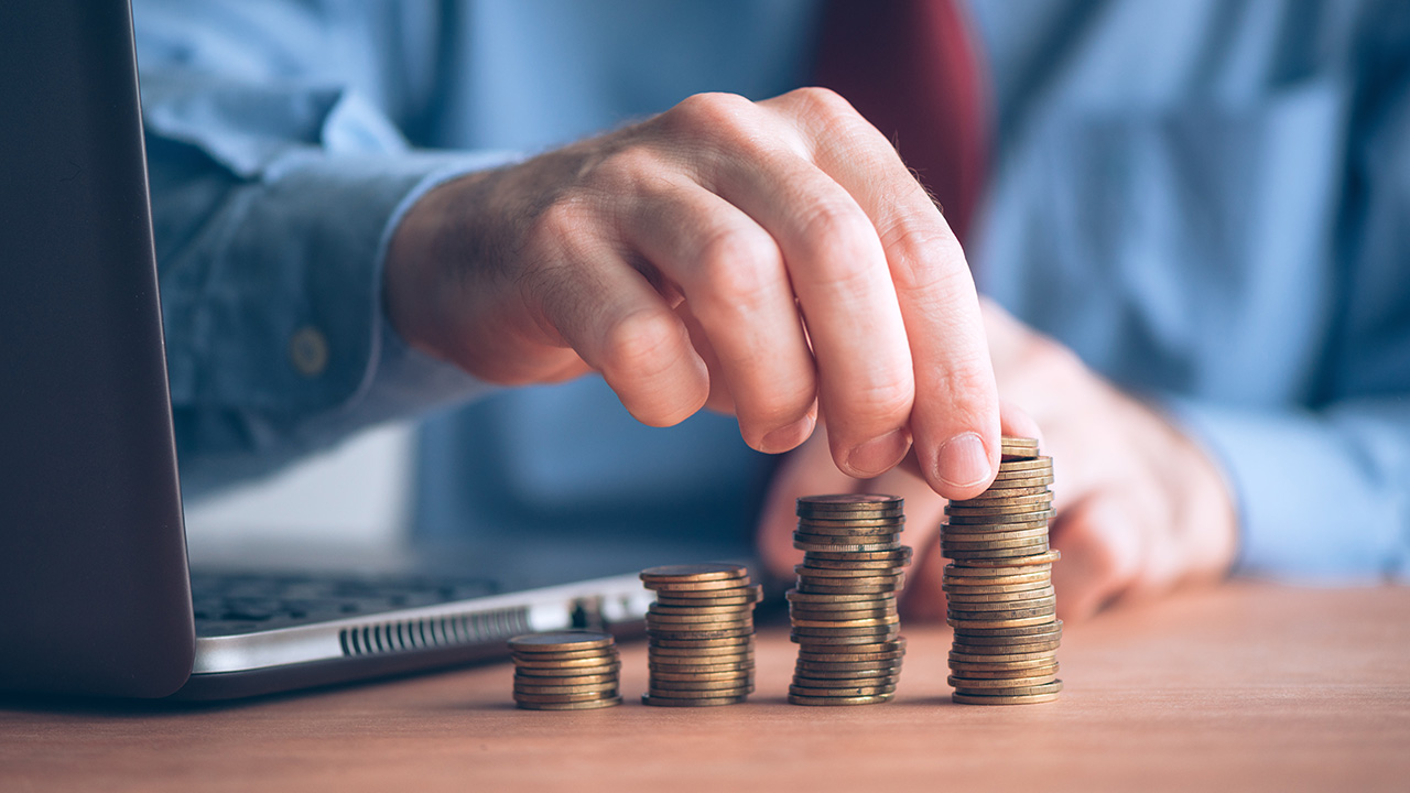 Businessman with stacked money coins on office desk