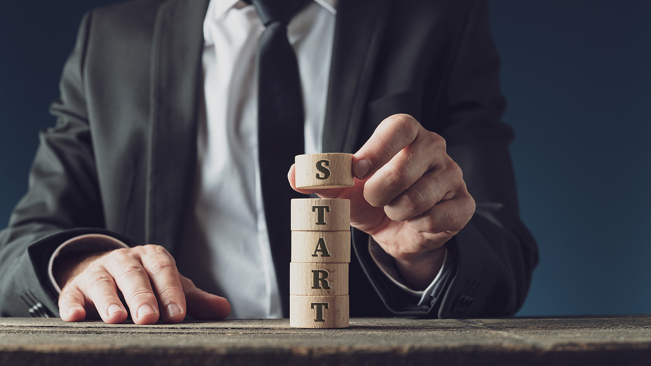 Businessman stacking wooden cut circles to assemble the word Start