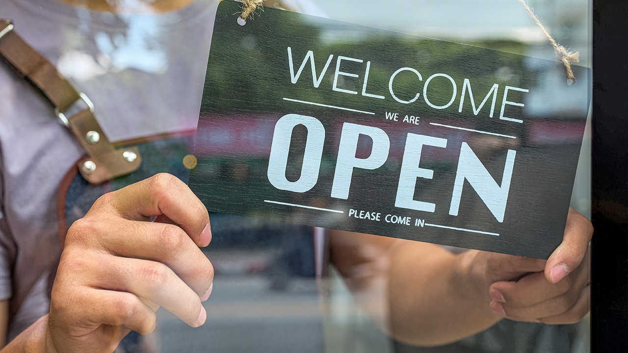 Close-up of the Business owner hand holding an open sign for service