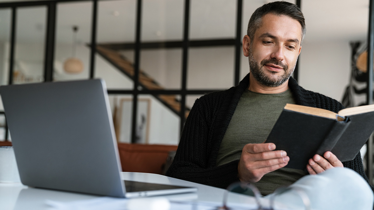 Confident young businessman reading book in the office