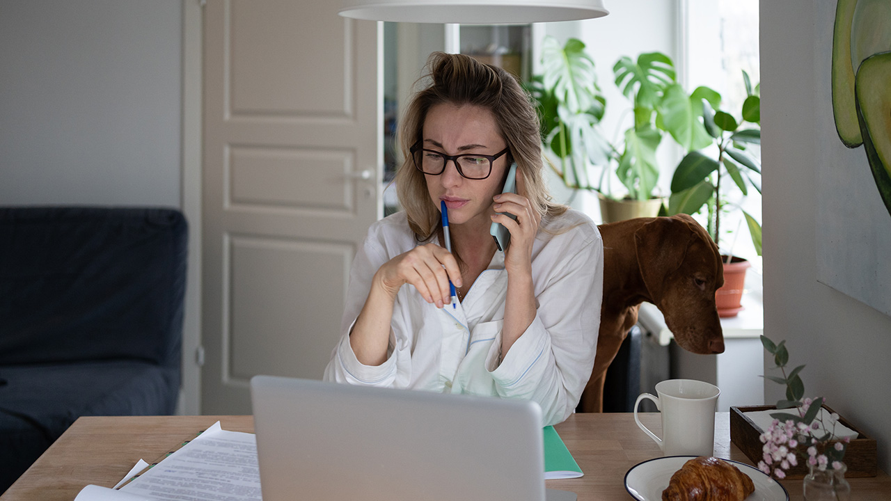 Remote employee woman sitting at desk with dog at home