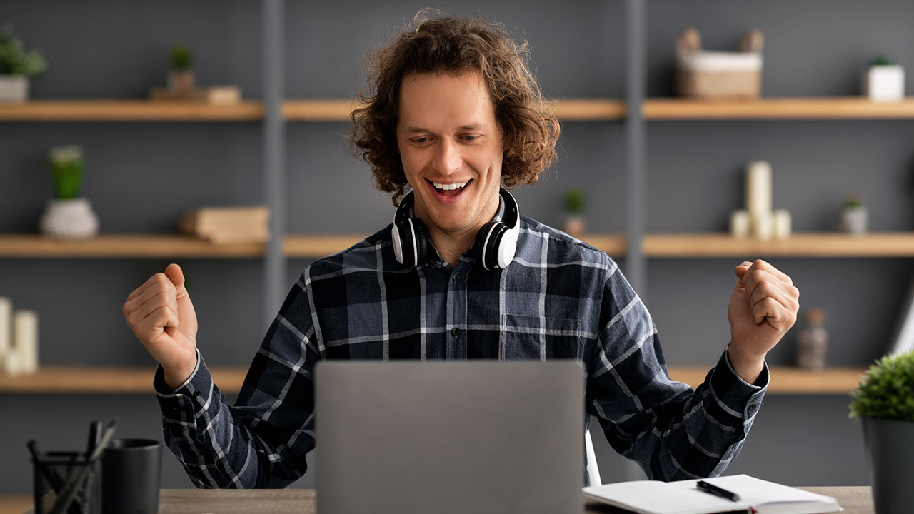 Joyful Young Entrepreneur at Laptop Celebrating Business Success