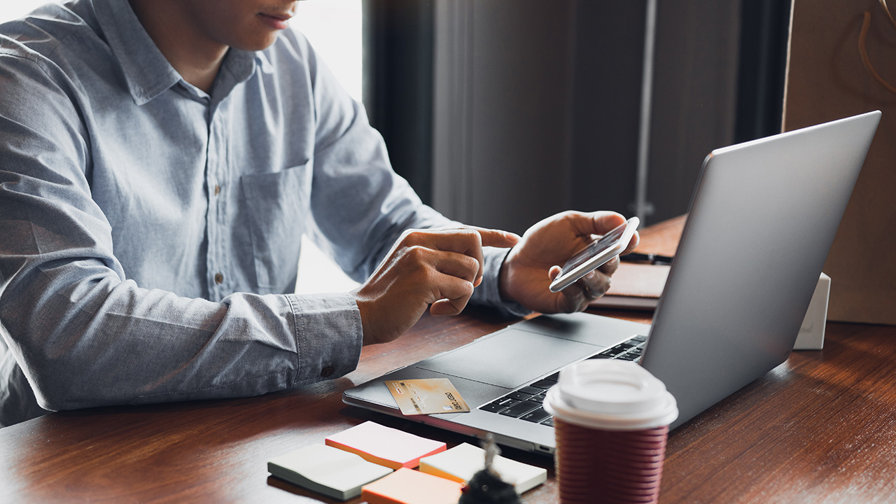 Entrepreneur holding smart phone and using laptop