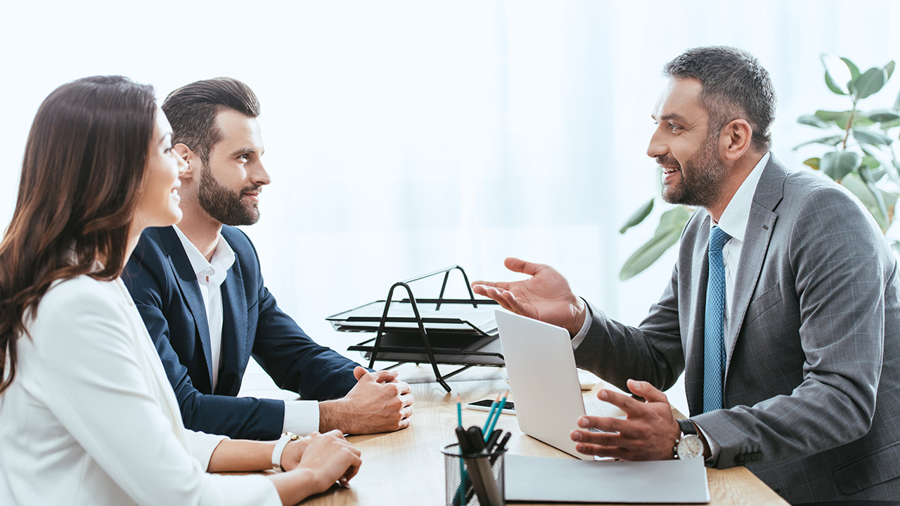 Handsome advisor in suit talking with investors at workplace