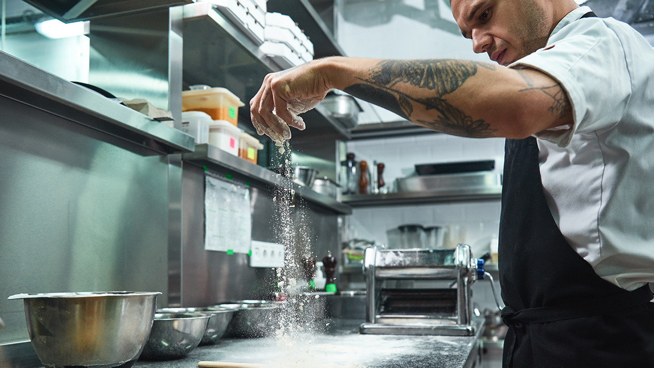 Handsome young chef with black tattoos on his arms