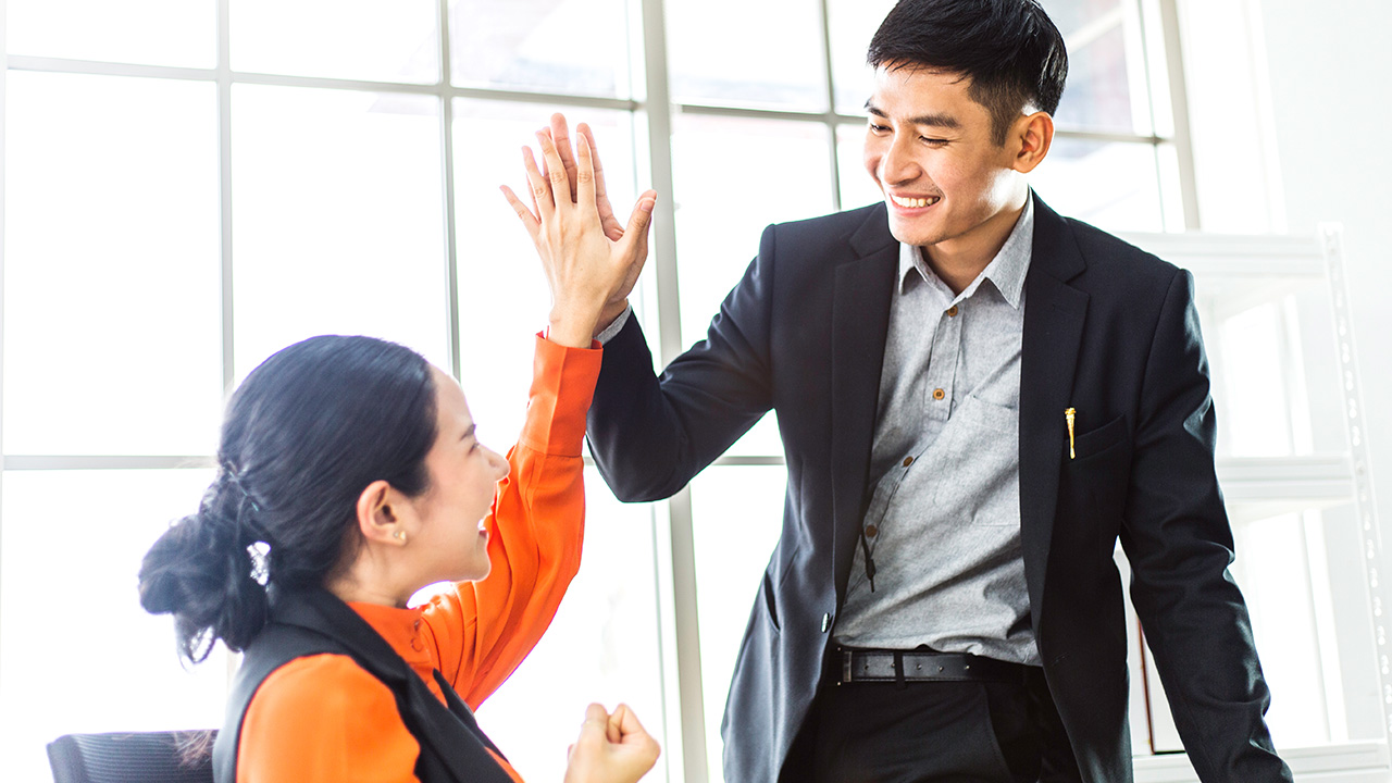 Successful business man and woman giving high five for project success