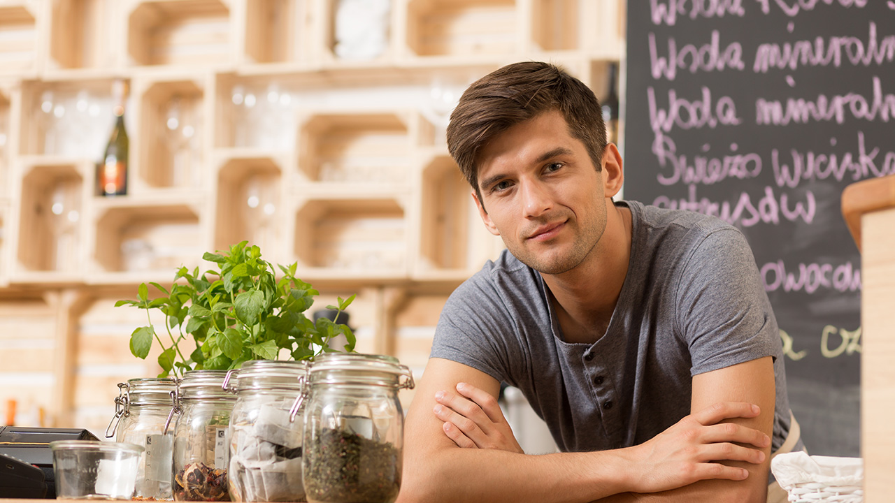 Handsome coffeehouse owner standing behind the counter