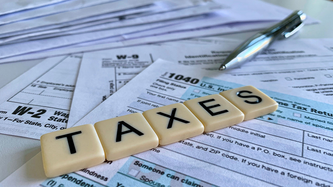 Letter tiles with the word TAXES on a variety of tax forms