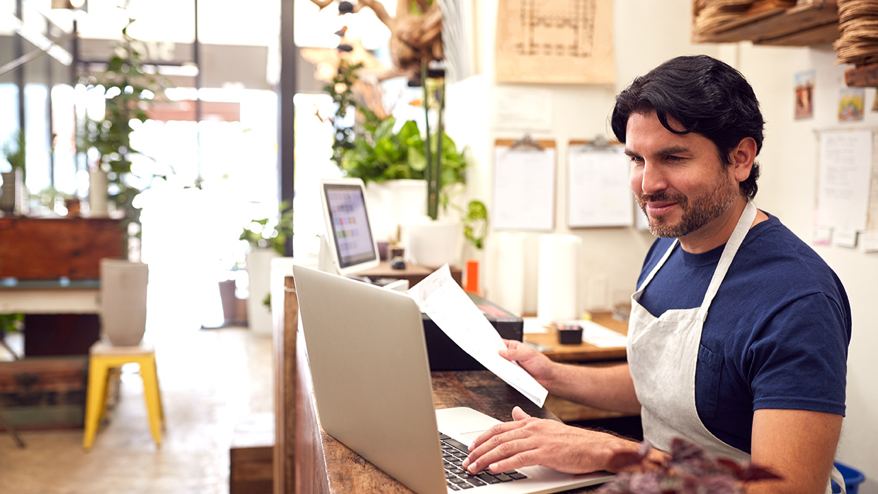 Male Sales Assistant Working On Laptop