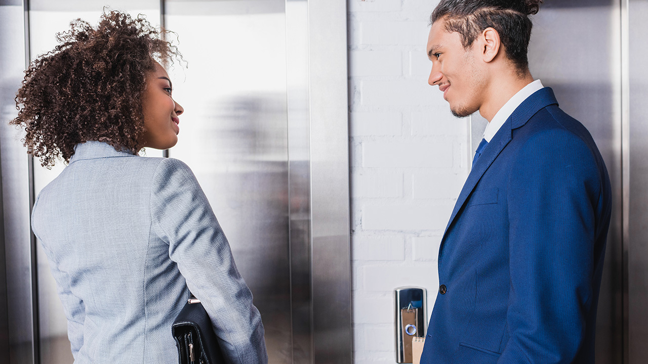 Smiling businessman and businesswoman talking by an elevator