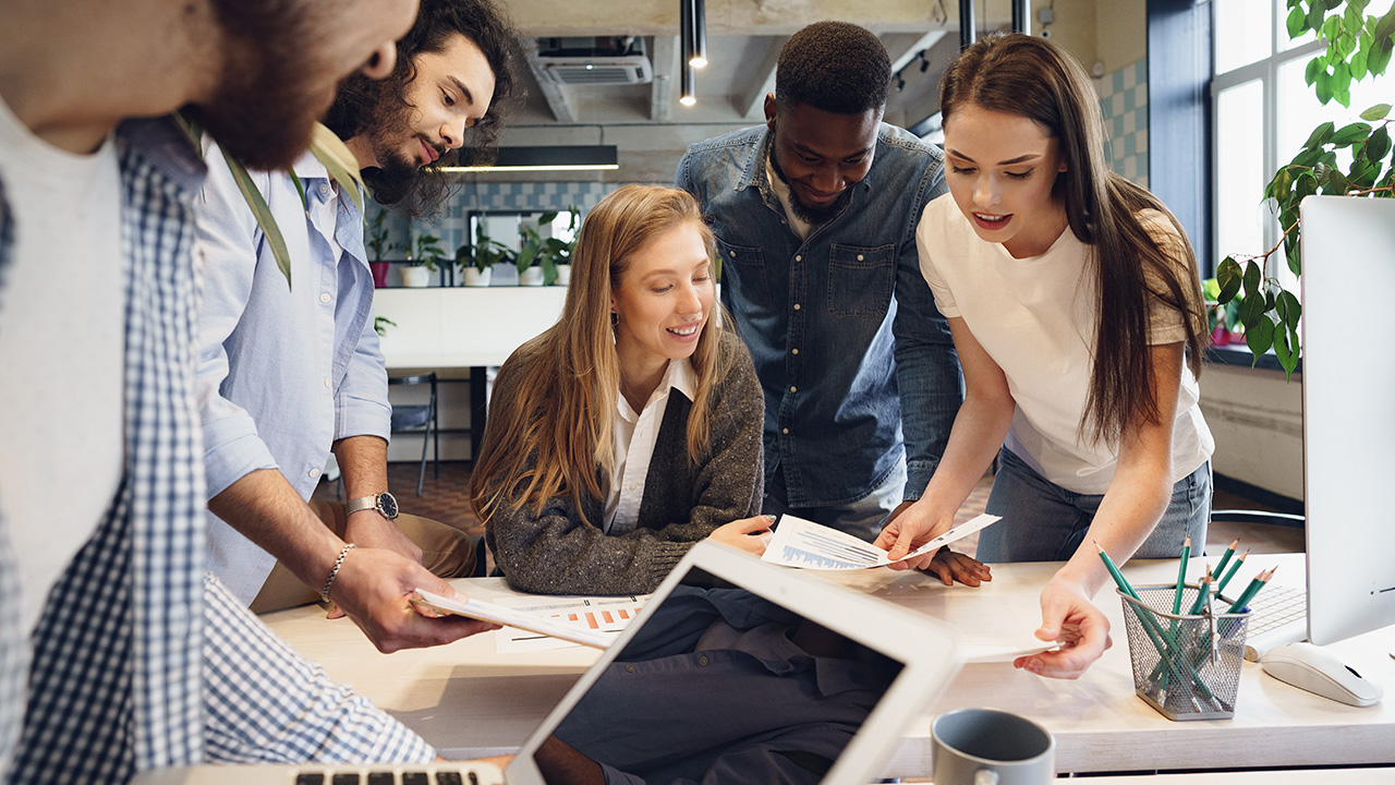 Team of diverse coworkers in modern office discuss their project together