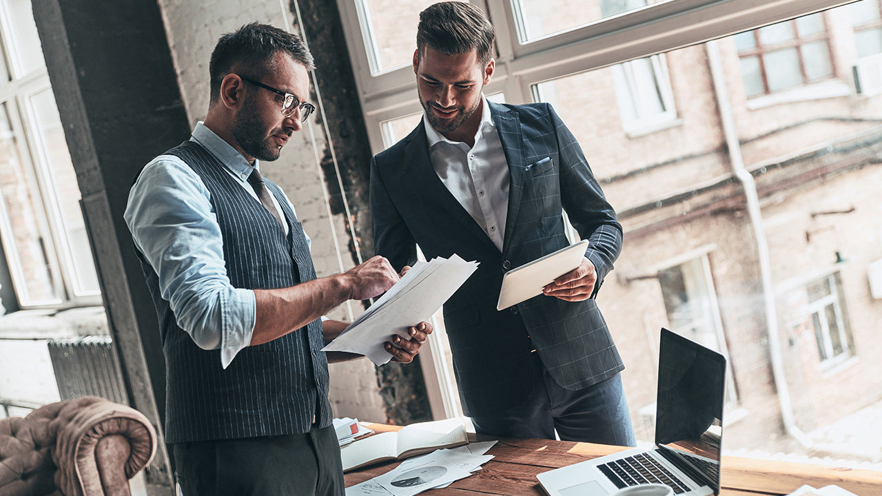 Two young modern men in formalwear working together