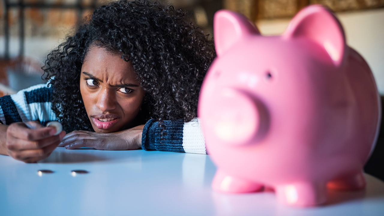 Thoughtful confused woman with piggy bank
