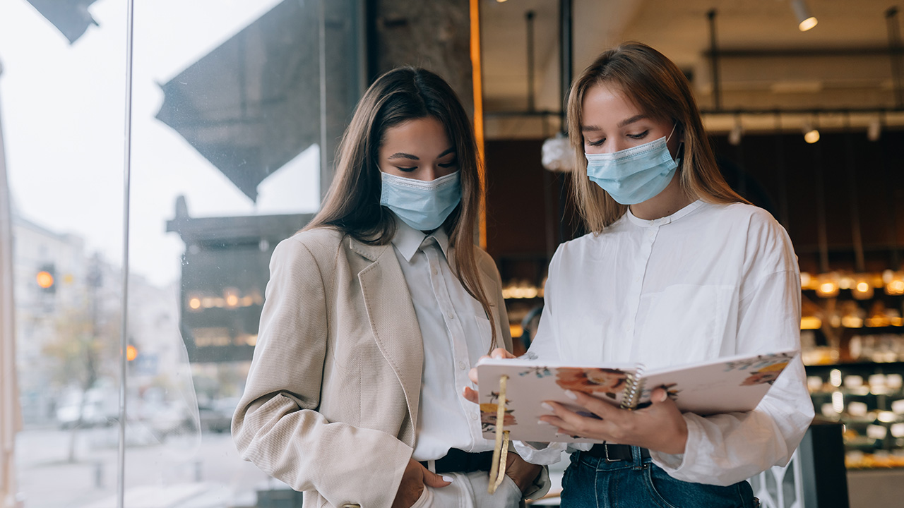 Two businesswomen with face masks debating different views