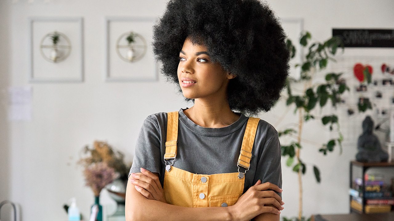 Young confident woman entrepreneur standing in cafe with arms crossed