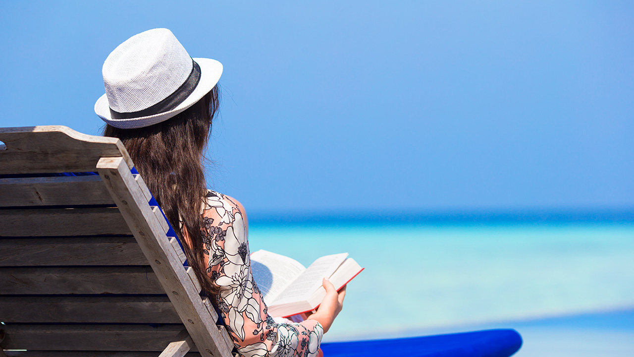 Young woman reading a book at the beach